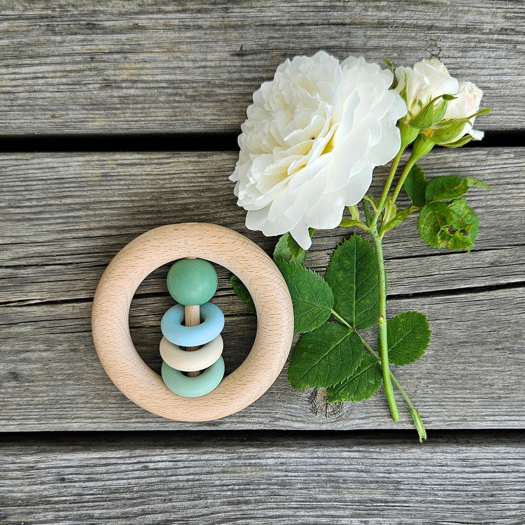 Green wooden baby rattle with smooth ring design for infants and Montessori inspired play