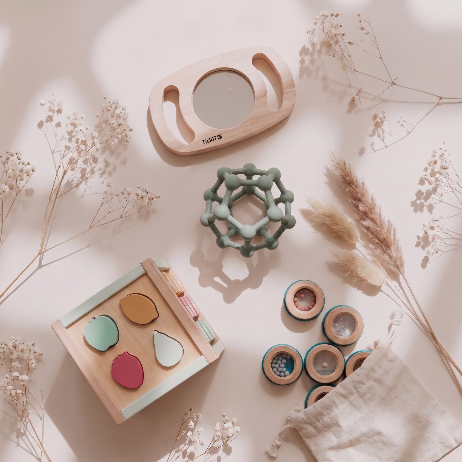 Flat lay of Montessori-inspired wooden sensory toys, baby mirror, shape puzzle, sensory ball and sound shakers on a neutral background.