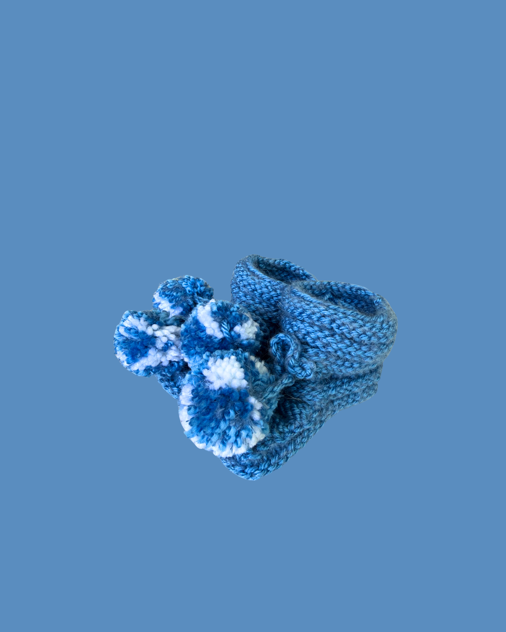 Hand knitted blue baby booties with blue and white pom poms for newborns