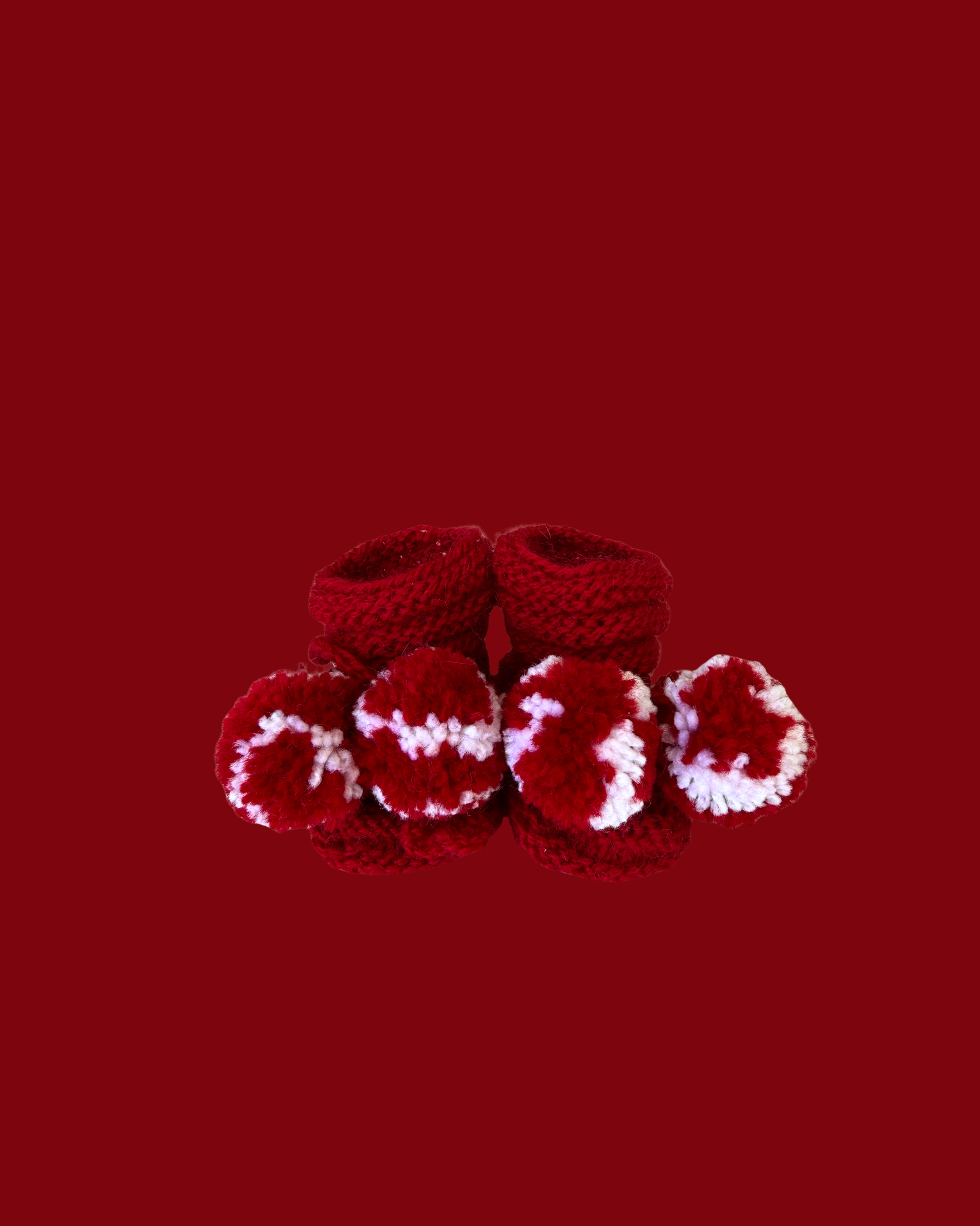 Hand knitted red baby booties with white pom poms for newborns