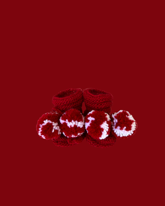 Hand knitted red baby booties with white pom poms for newborns