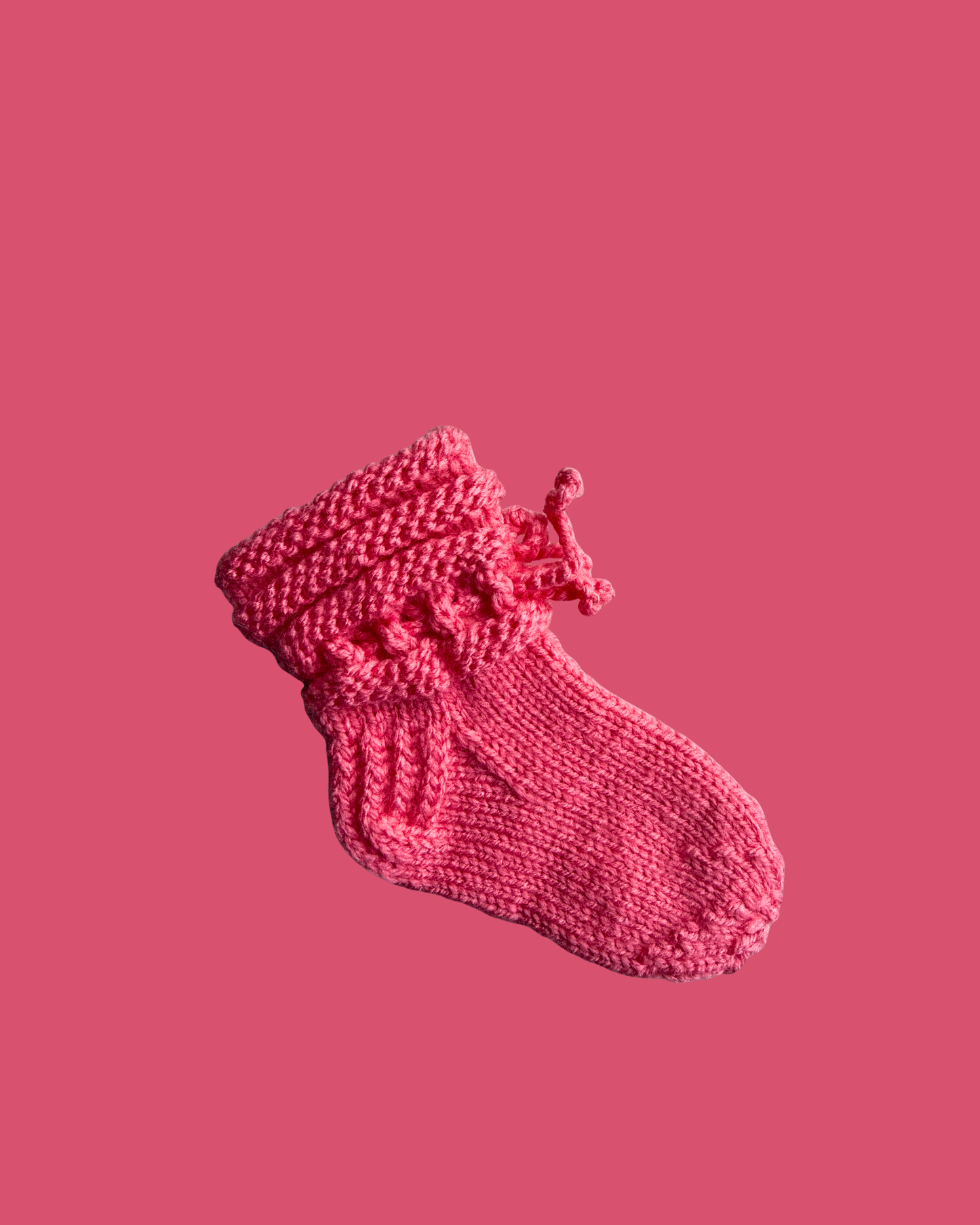 Hand knitted soft pink baby booties with decorative lace cuff for newborns
