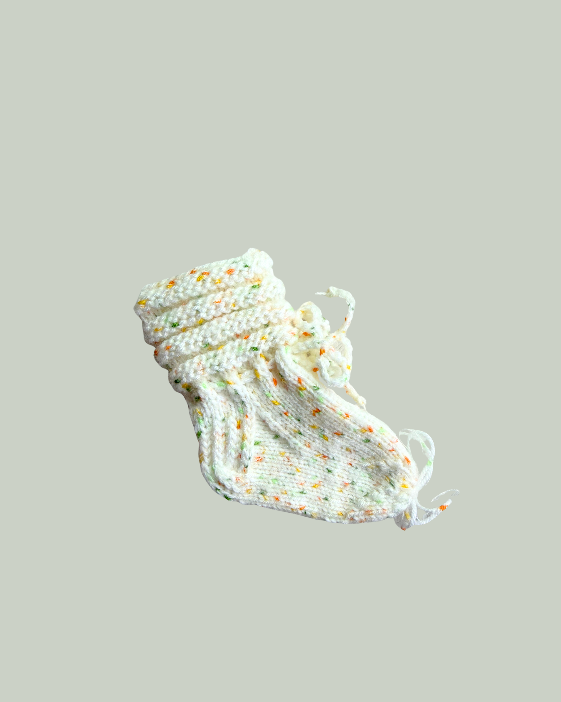 Hand knitted white baby booties with colorful speckled yarn for newborns