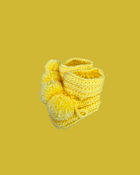 Hand knitted yellow baby booties with soft pom poms for newborns