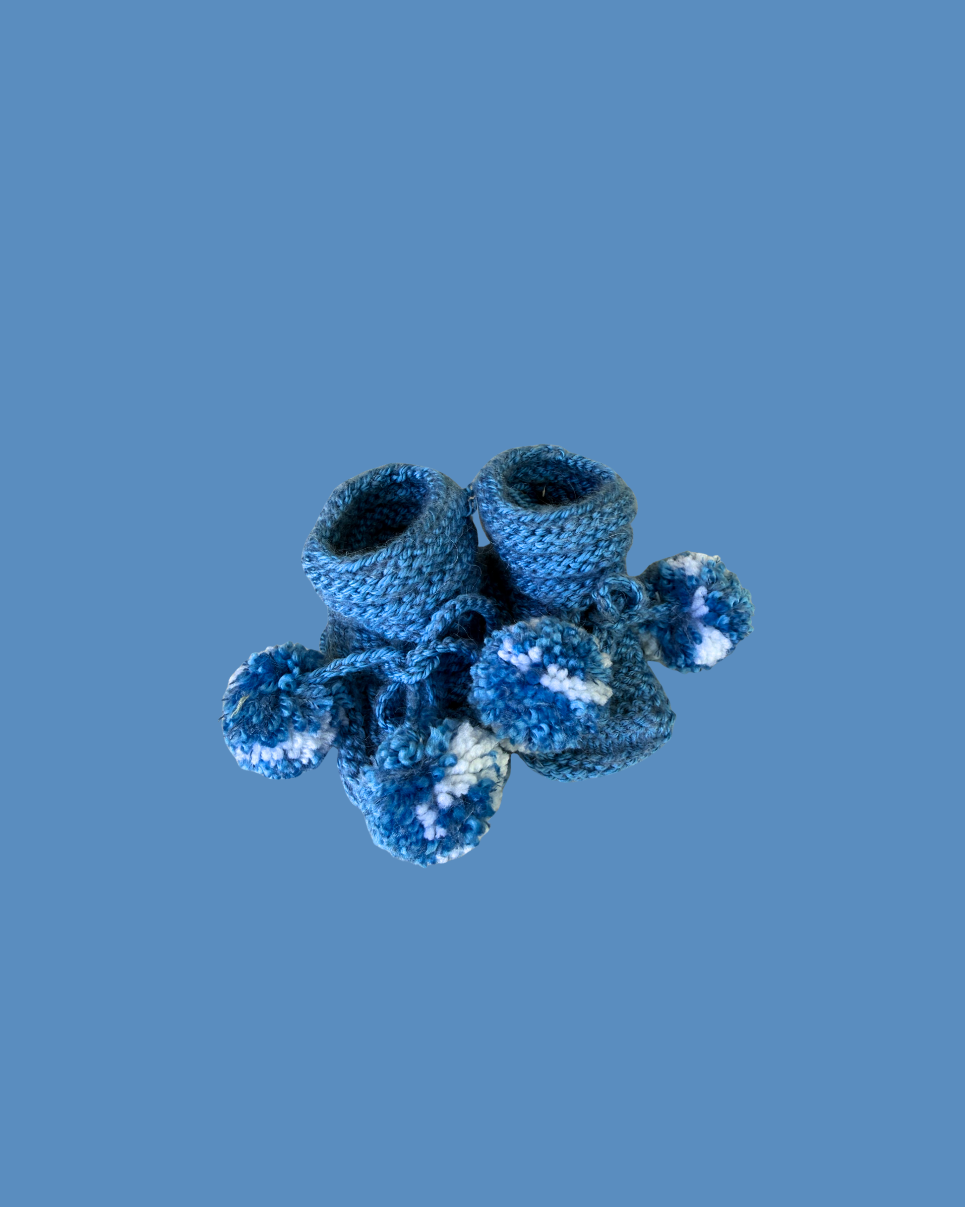 Soft hand knitted blue baby booties with decorative blue and white pom poms